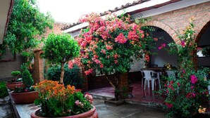 A courtyard with potted plants, a brick wall, and a tiled floor. - Villa Flores (Mascota)