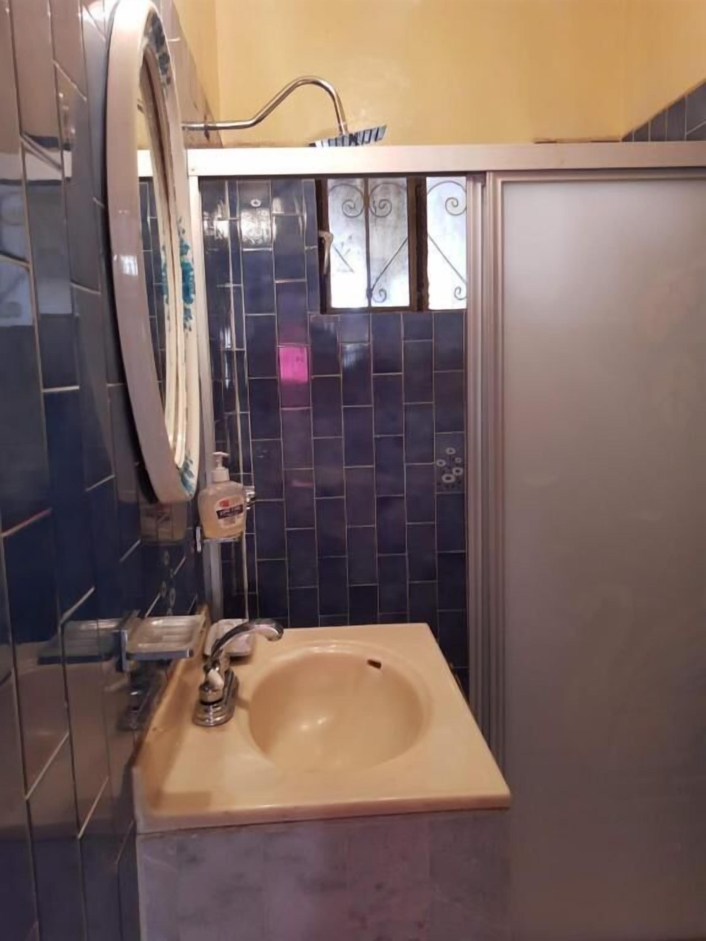 A bathroom with a sink, mirror, and tiled walls.