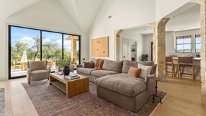 A spacious living room with a large window, a cozy sofa, a wooden coffee table, and a stone accent wall.