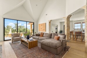 A spacious living room with a large window, a cozy sofa, a wooden coffee table, and a stone accent wall.