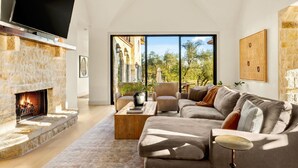 A living room with a stone fireplace, a large flat-screen TV, a sofa, and a coffee table.