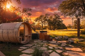 A wooden barrel-shaped structure with a door, a barrel, and a stone pathway.