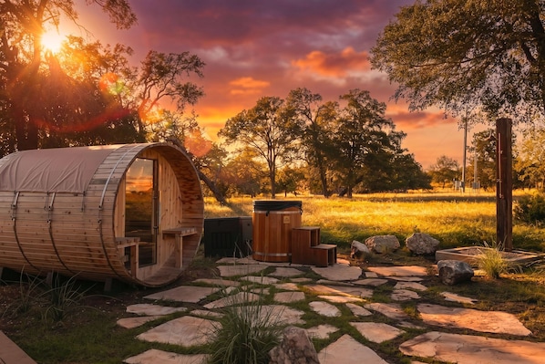 A wooden barrel-shaped structure with a door, a barrel, and a stone pathway.