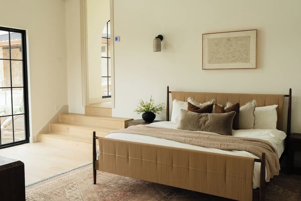 Ein Schlafzimmer mit Bett, Treppe, Blumentopf und einem gerahmten Bild an der Wand.