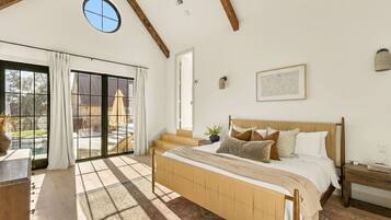 A bedroom with a large bed, a window with curtains, a view of a pool, and a wooden ceiling.