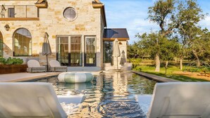 A stone house with a swimming pool, outdoor seating, and a pergola. - Deep Eddy Ranch: 10 Acres, Pool, Pickleball, Sauna (Dripping Springs)