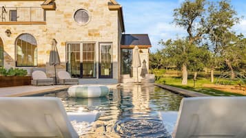 Una casa de piedra con piscina, mobiliario de exterior y una pérgola.