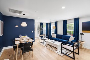 Ein modernes Wohnzimmer mit einem blauen Sofa, einem Esstisch und Stühlen.