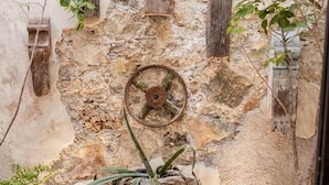 A rustic outdoor area with a stone wall, wooden beams, and a rustic wheel. - Casa Ek: House•Safe•Fast WiFi•Pool•Walkable  area (Mérida)