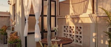 An outdoor patio area with a wooden pergola, string lights, a table, and potted plants.