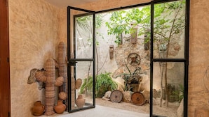 A room with a large glass door leading to an outdoor garden, wicker furniture, and rustic decor. - Casa Ek: House•Safe•Fast WiFi•Pool•Walkable  area (Mérida)