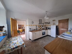 A kitchen with a wooden table, a stove, a microwave, and a sink. - Former wine estate with breathtaking panoramic views! (Canelli)