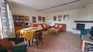 A living room with a dining table, chairs, a sofa, a fireplace, and a bookshelf. - Former wine estate with breathtaking panoramic views! (Canelli)