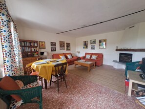 A living room with a dining table, chairs, a sofa, a fireplace, and a bookshelf. - Former wine estate with breathtaking panoramic views! (Canelli)