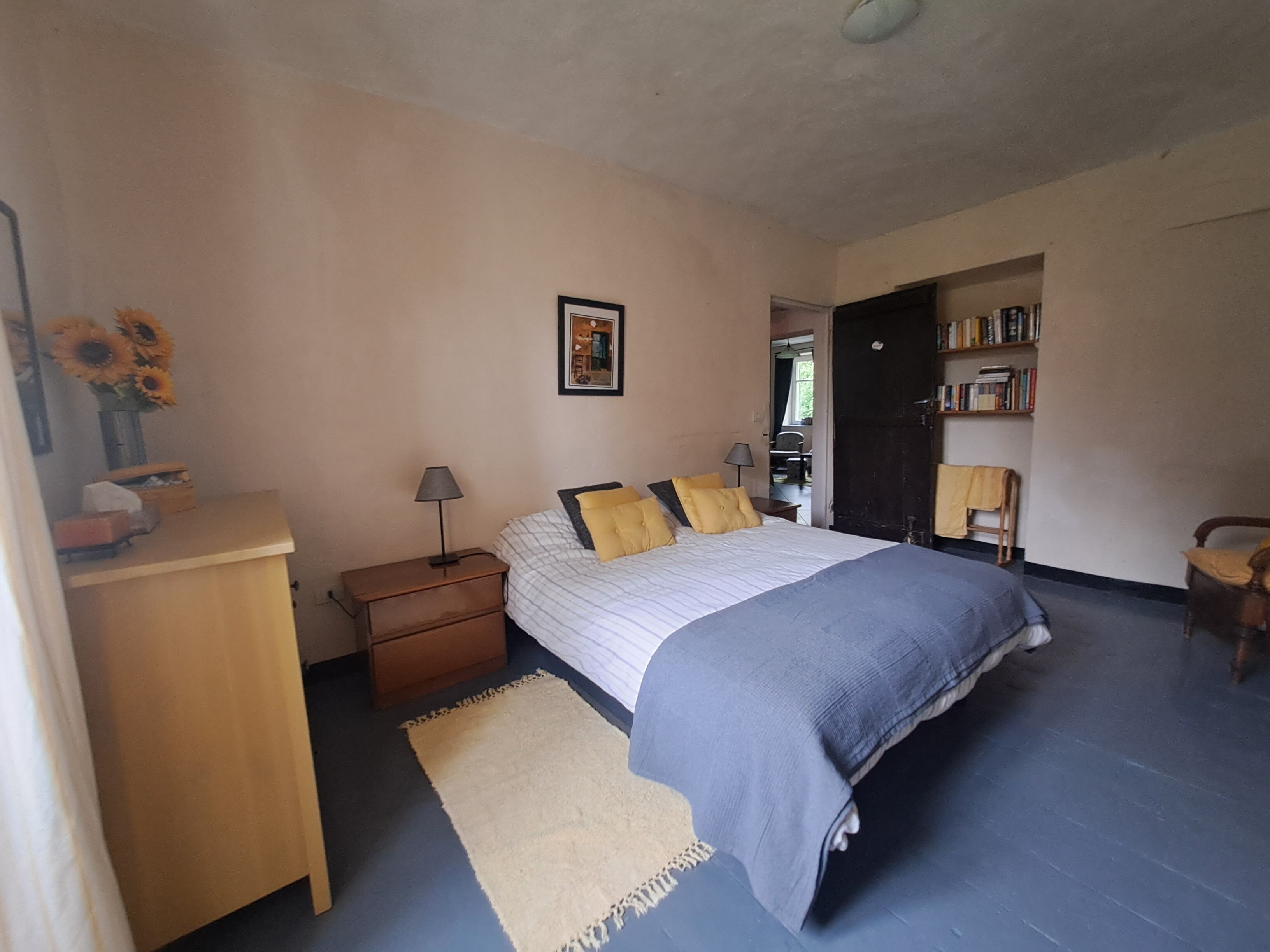 A bedroom with a bed, bedside table, lamp, and a rug.