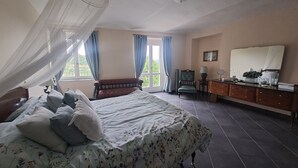 A bedroom with a bed, a chair, a dresser, and a window with curtains. - Former wine estate with breathtaking panoramic views! (Canelli)