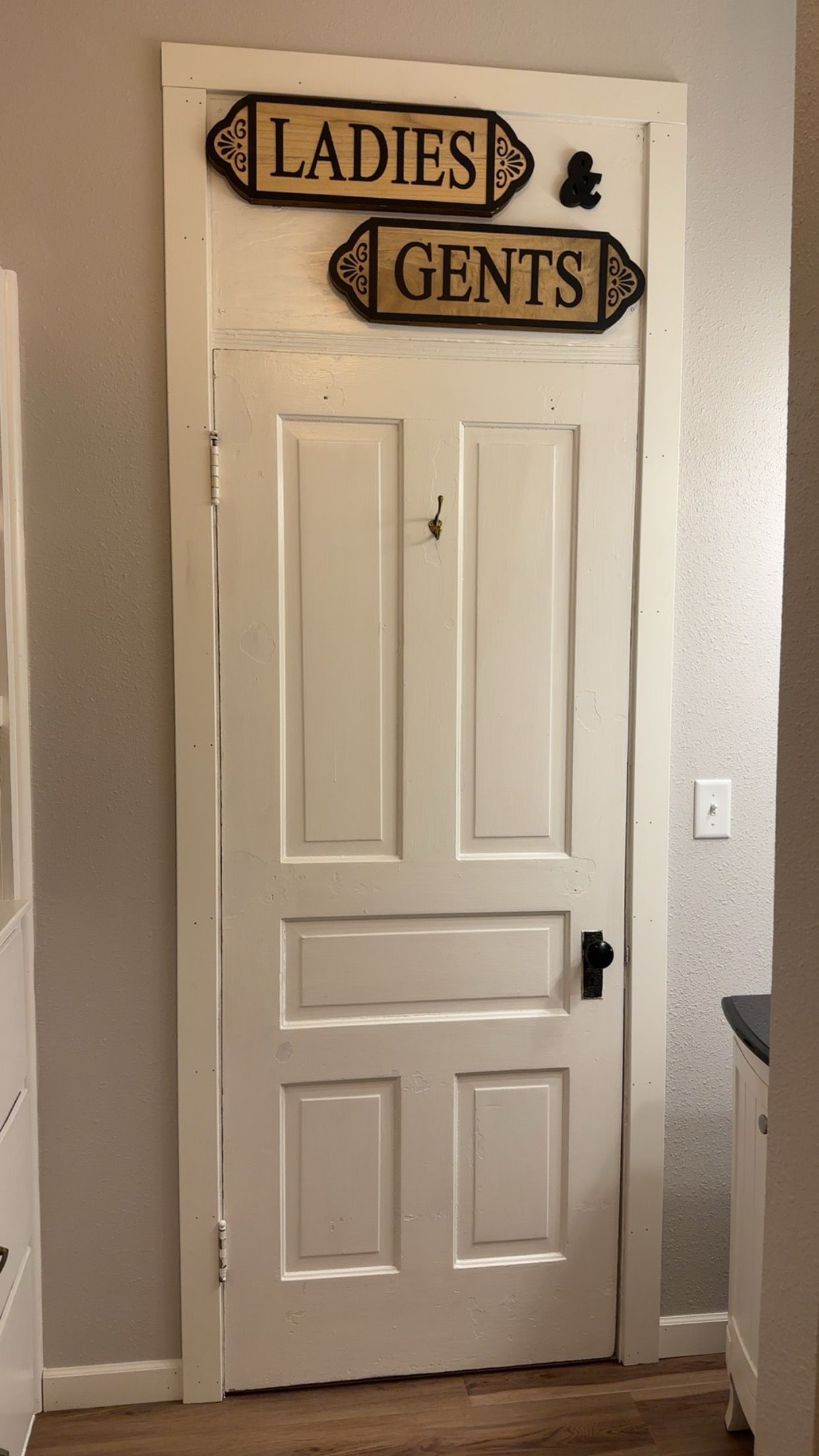 A white door with two signs above it reading 'Ladies' and 'Gents.'