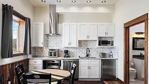 Una cocina compacta con armarios blancos, microondas, tostadora y pileta.