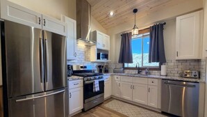A modern kitchen with stainless steel appliances, wooden flooring, and a view of the outdoors. - Elk Suite: Epic Paradise Valley Views will amaze. (Emigrant)