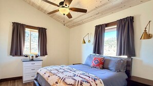A bedroom with a bed, a nightstand, a dresser, a ceiling fan, and a window with curtains. - Elk Suite: Epic Paradise Valley Views will amaze. (Emigrant)