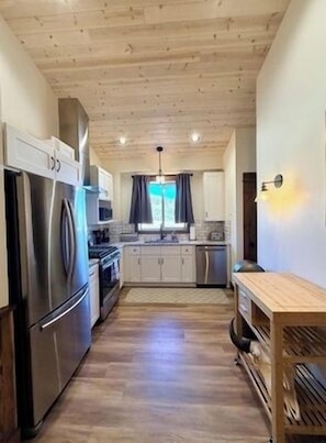 Una cocina moderna con techo de madera, electrodomésticos de acero inoxidable y una isla central.