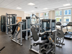 A gym with various exercise machines, a bench press, and a treadmill.