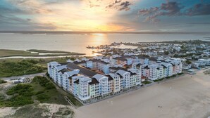 A coastal residential area with multi-story buildings, a beach, and a sunset view. - New! Oceanfront / Pool / Boat / Surf / Kayak, Swim (Virginia Beach)