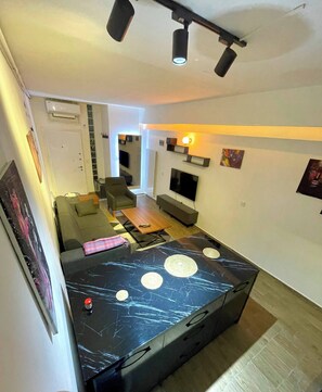 A modern living room with a large black table, a sofa, a TV, and a ceiling fan. - Cosy Flat Neartaksim and Nişantaşi (Istanbul)