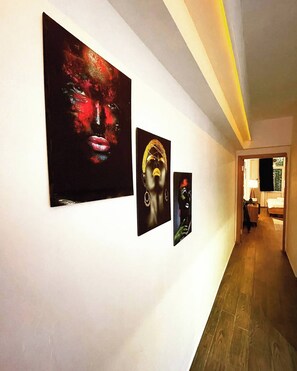 A hallway with three artworks on the wall, a wooden floor, and a door leading to another room. - Cosy Flat Neartaksim and Nişantaşi (Istanbul)
