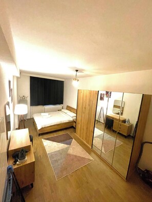 A bedroom with a bed, bedside table, lamp, mirror, dresser, and a radiator. - Cosy Flat Neartaksim and Nişantaşi (Istanbul)