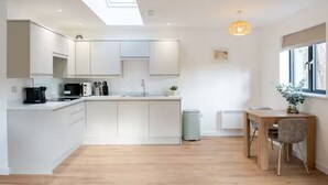 A modern kitchen with white cabinets, a central island, and a dining area with a wooden table and chairs.