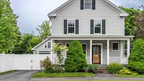 A two-story house with a front porch, a garage, and a well-maintained lawn. - Sunny House, By The Beach, Minutes From Portland (South Portland)