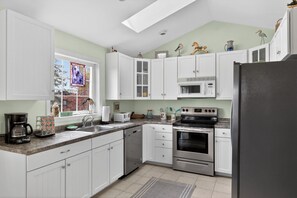 A kitchen with white cabinets, a microwave, a stove, and a refrigerator.