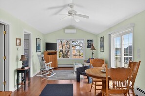 Una habitación acogedora con una mesa de comedor, sillas, un sillón mecedora, televisión y un ventanal grande.