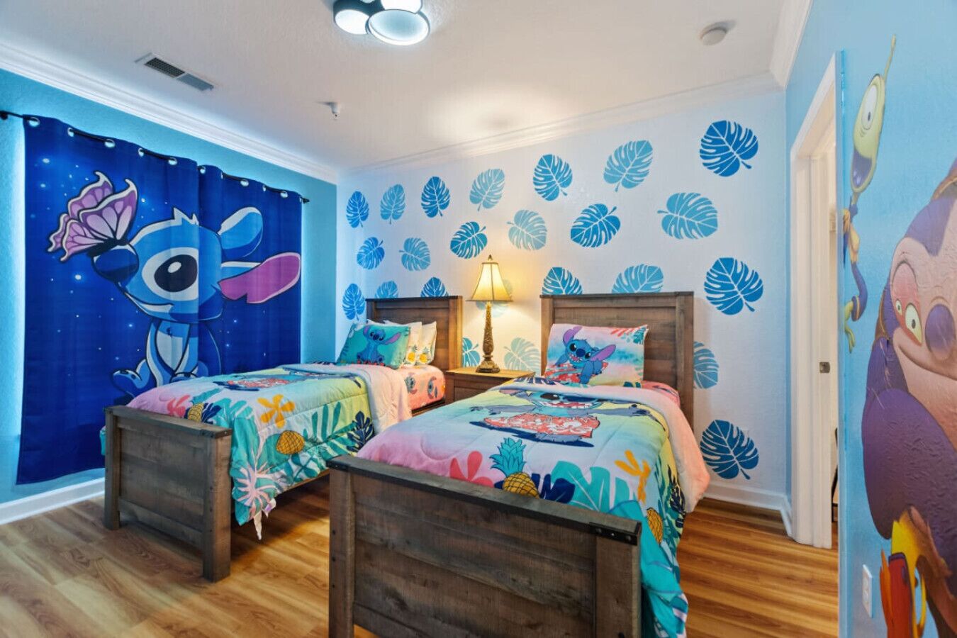 Un dormitorio con dos camas, una mesita de noche, una lámpara y un mural en la pared.