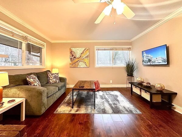 A living room with a sofa, coffee table, TV, and artwork.