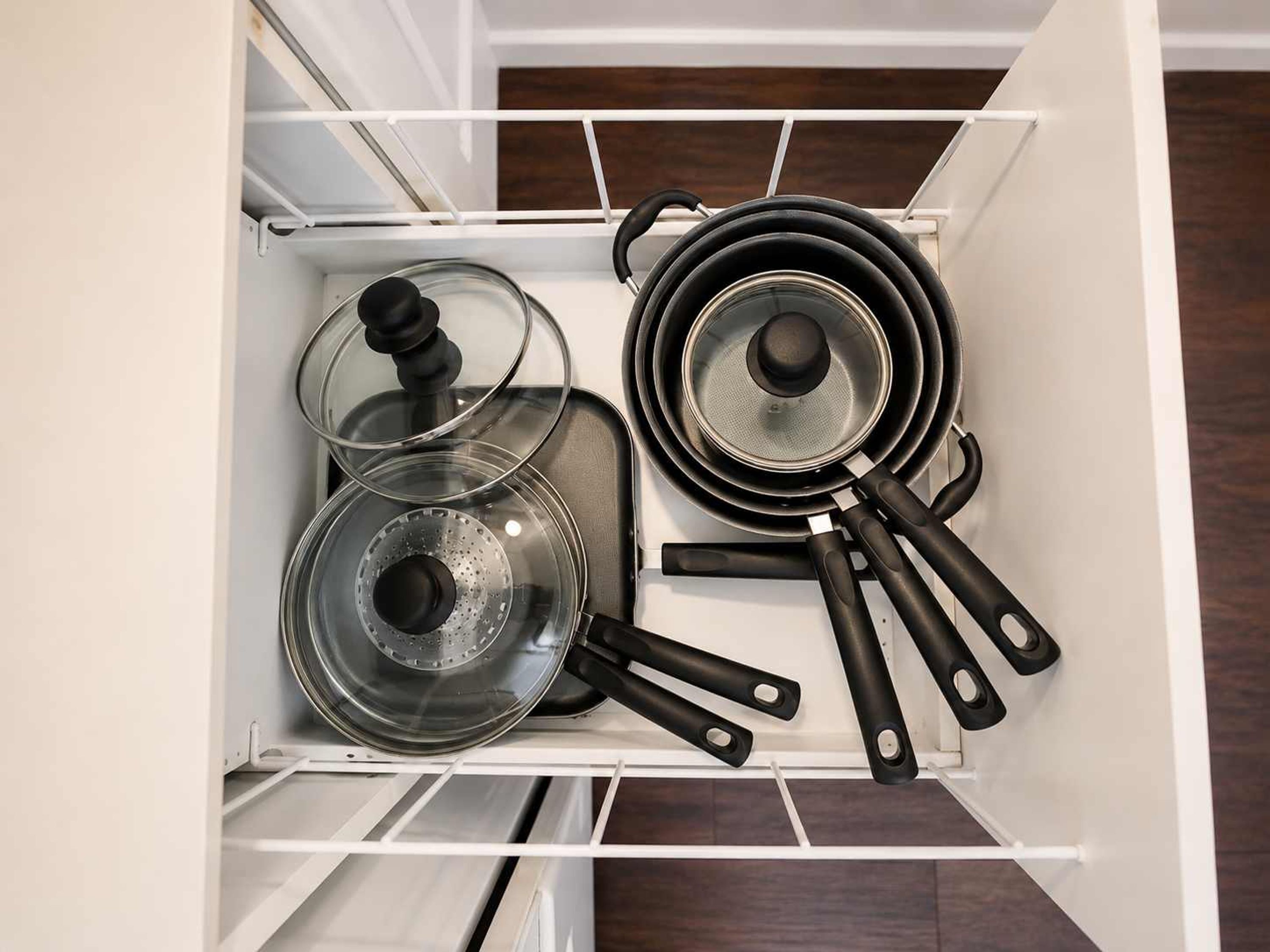Ein Küchenschrank mit darin gelagerten Töpfen und Pfannen.