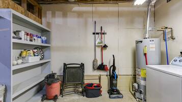 A laundry room with shelves, a vacuum cleaner, a water heater, and a washing machine.