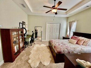 A bedroom with a bed, a desk, a chair, a mirror, a wardrobe, and a ceiling fan. - Tranquil Home in Cumming (Cumming)