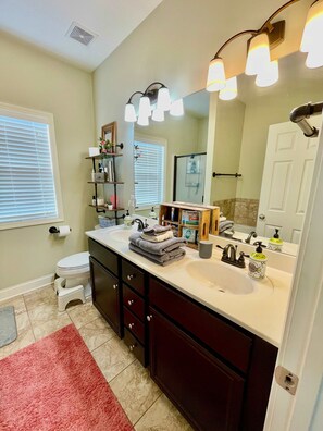 A bathroom with a white sink, dark wooden vanity, a large mirror, and a red rug. - Tranquil Home in Cumming (Cumming)