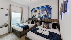 Habitación de hotel con dos camas, un ventanal grande, una araña y un mural en la pared.
