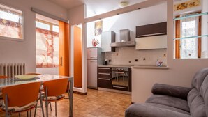 Eine moderne Küche mit Essbereich, einer Couch und einem Fenster mit Jalousien.