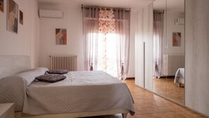 Ein Schlafzimmer mit Bett, Heizkörper, Spiegel und Bildern an den Wänden.