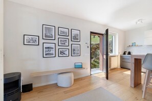 Une cuisine moderne avec un plancher en bois, un banc intégré et un mur décoré de photographies en noir et blanc encadrées.