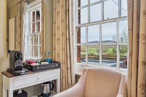 Une pièce avec une grande fenêtre, un bureau blanc avec une machine à café, un miroir et une chaise.