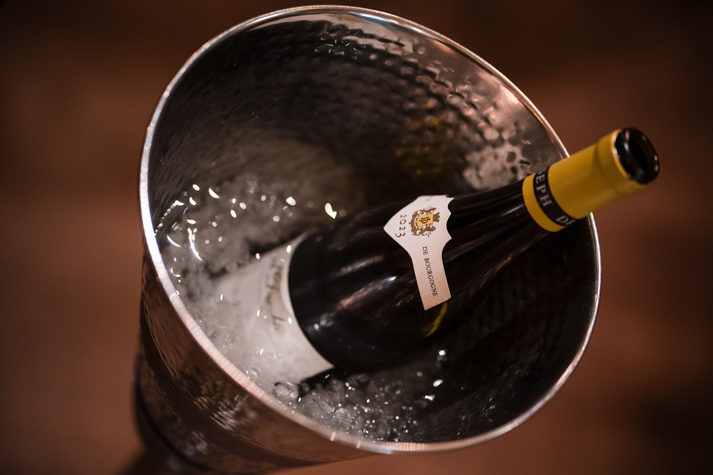 A bottle of wine in a metallic bucket.