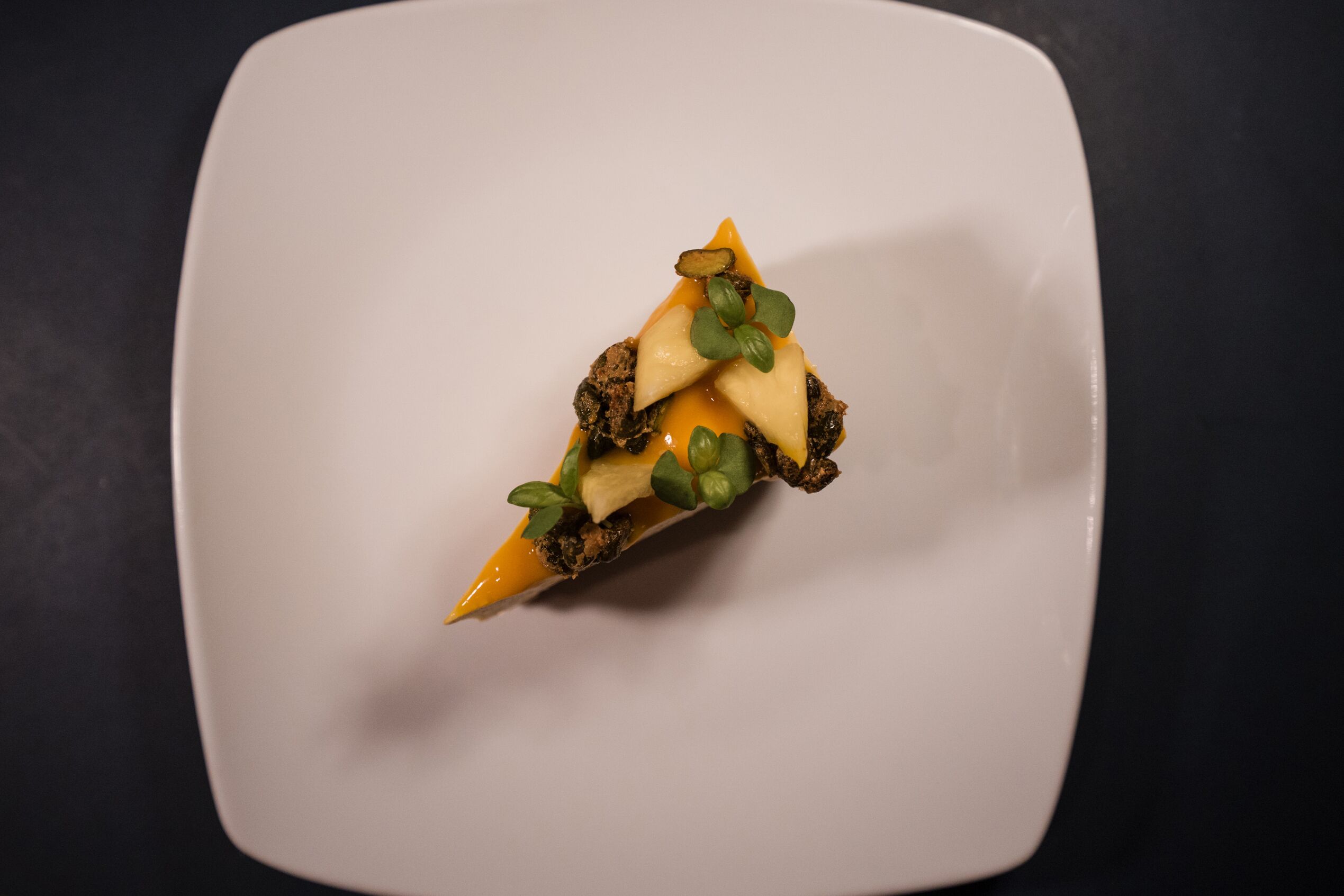 A square white plate with a triangular food item on it.