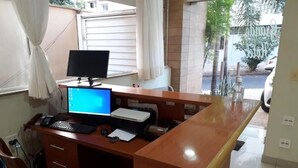 A wooden desk with a computer, keyboard, and mouse, a chair, and a window with curtains. - novo grande hotel  (Ribeirão Preto)