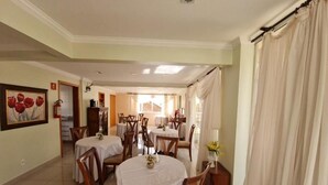 A dining area with multiple tables and chairs, a painting on the wall, and a view into another room. - novo grande hotel  (Ribeirão Preto)