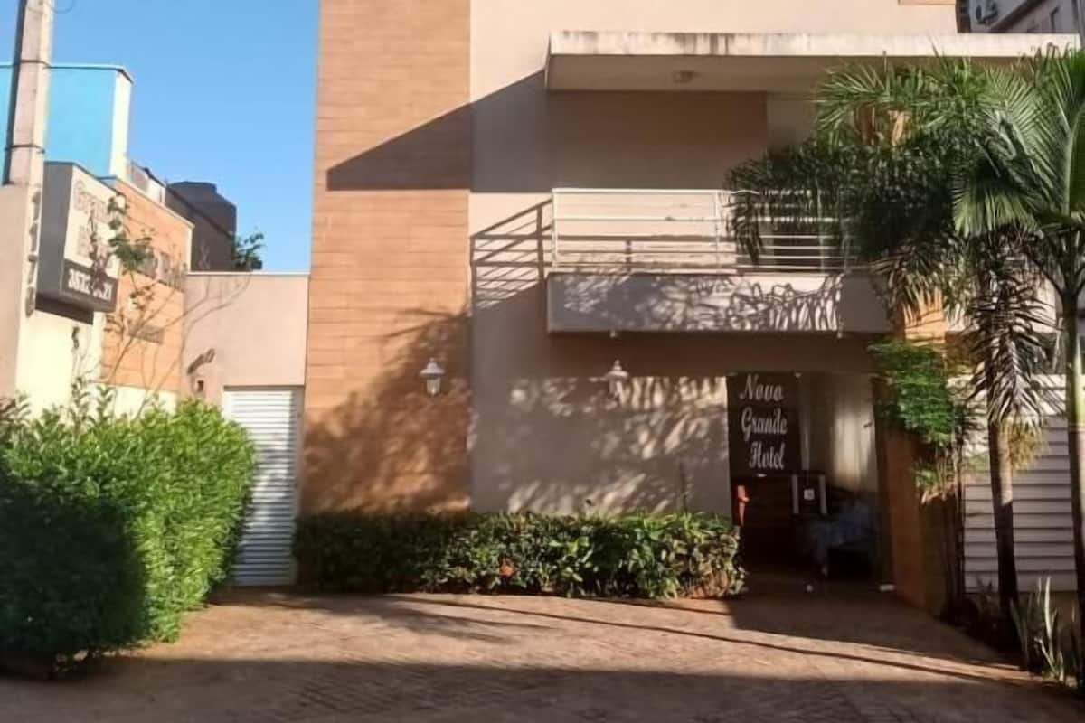 A hotel entrance with a modern design, a visible sign for 'Hotel Grande Hotel,' and a gated driveway.